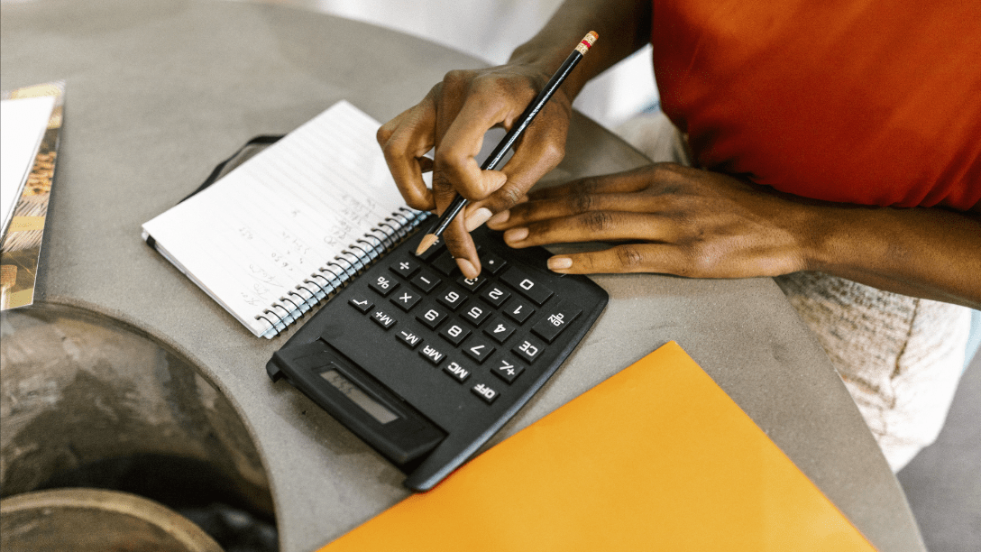 close-up of a hand using a calculator and pen for calculations